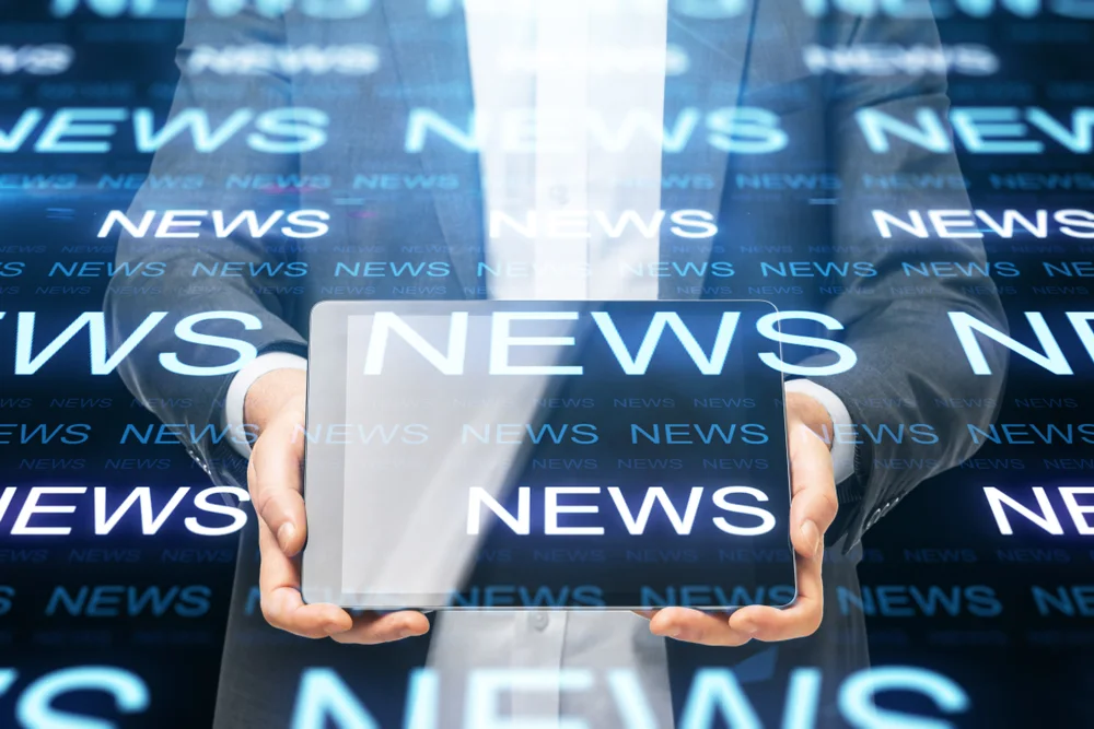 Businessman holding tablet with glowing news hologram interface. News and information concept.